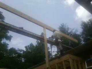 Carpenter setting a ridge beam over a new addition frame — Ice Dam Removal by Roofing Brothers in Barnardsville
