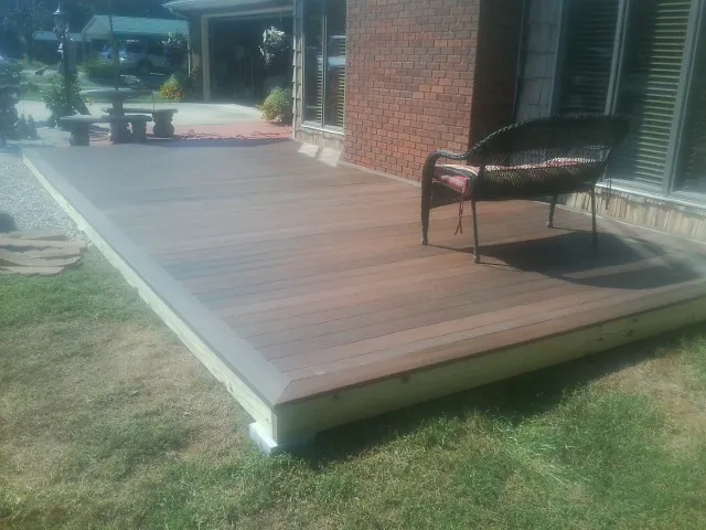 New wood deck and wicker chair beside a brick house in Barnardsville