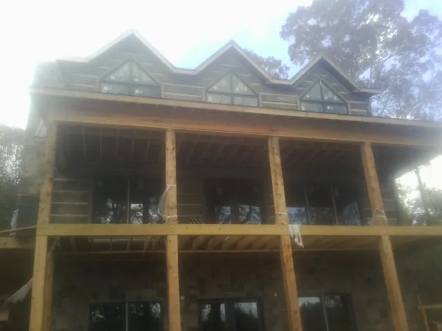 Dormers and porch framing on a large log home under construction — Roof Coating work by our crew in Barnardsville