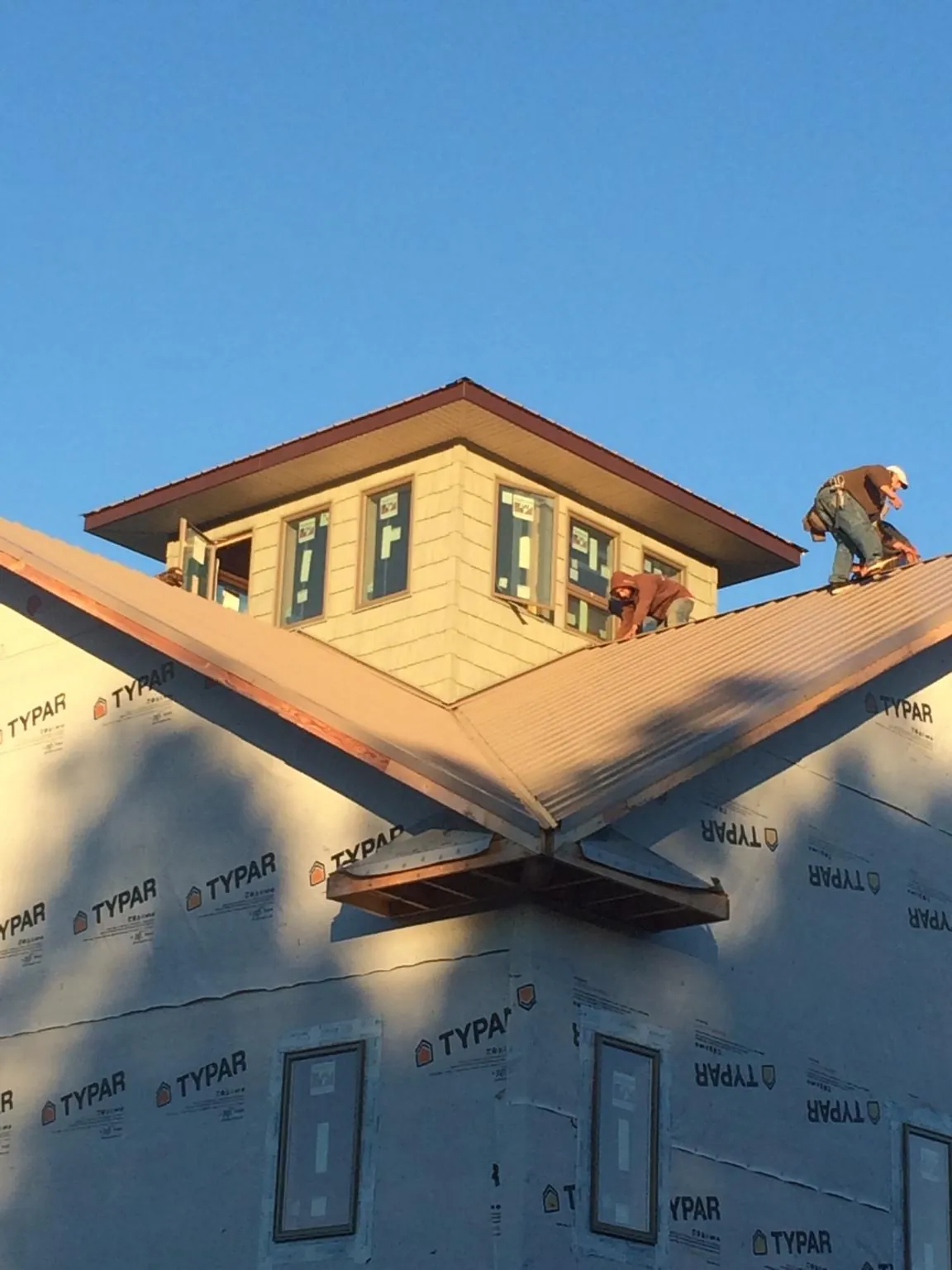 Roofers working around a rooftop cupola on a new metal roof at sunset — Roof Waterproofing in Barnardsville by Roofing Brothers